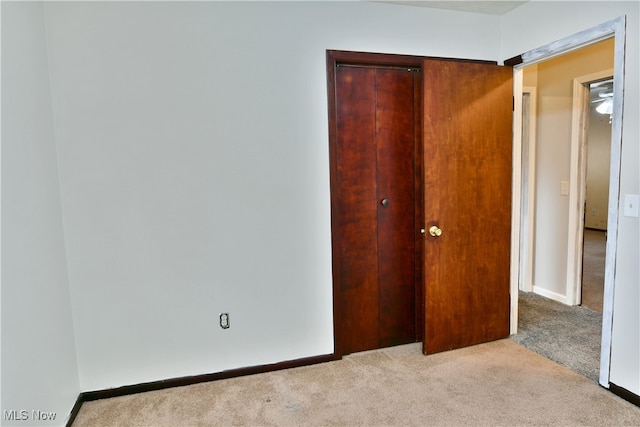 unfurnished bedroom with a closet and light colored carpet