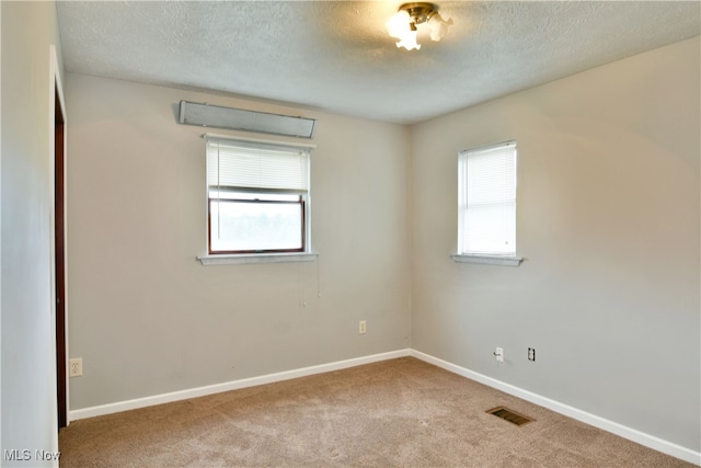 carpeted empty room with a textured ceiling