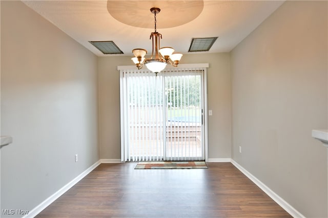 unfurnished dining area featuring an inviting chandelier and dark hardwood / wood-style flooring