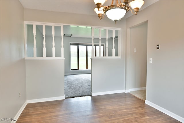 unfurnished room with an inviting chandelier and hardwood / wood-style flooring