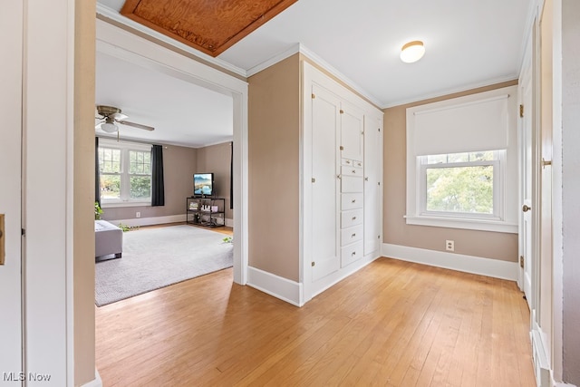 interior space with ornamental molding, ceiling fan, and light hardwood / wood-style floors