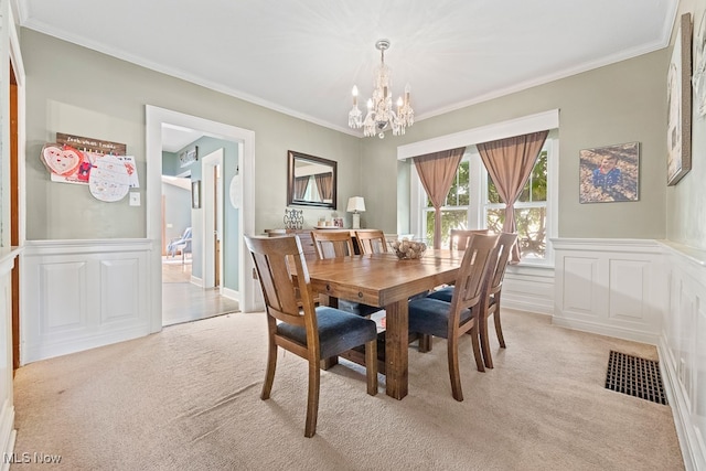 dining area featuring crown molding, an inviting chandelier, and light colored carpet