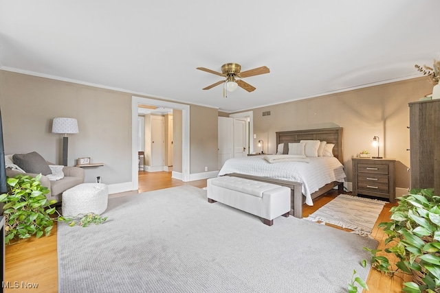 bedroom with crown molding, ceiling fan, and light hardwood / wood-style flooring