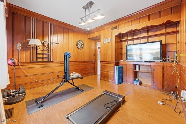 exercise area with wood-type flooring, wood walls, and crown molding