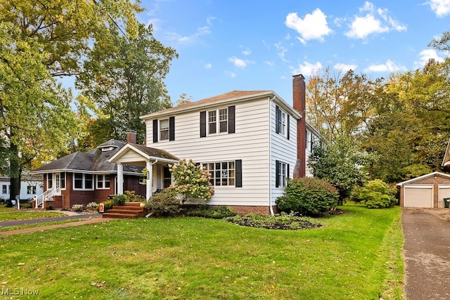 view of front of home with a garage, an outbuilding, a front lawn, and covered porch