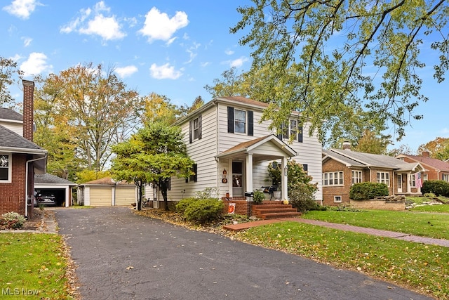 view of front of property featuring a garage, a front yard, an outdoor structure, and covered porch