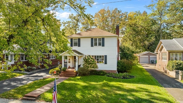 view of front of home featuring a front yard, a garage, and an outbuilding