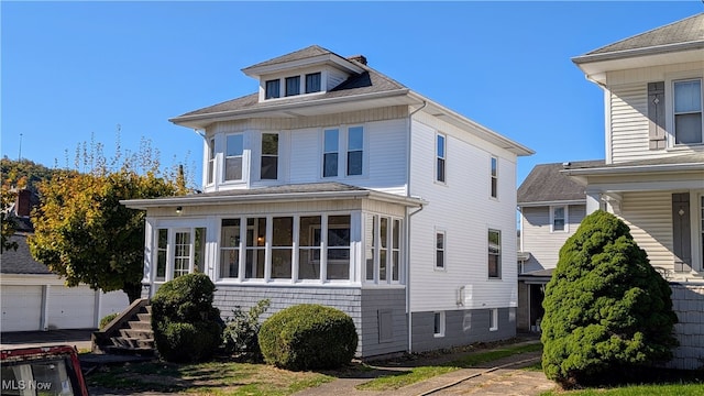 view of property featuring a garage and a sunroom