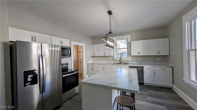 kitchen featuring a healthy amount of sunlight, hanging light fixtures, stainless steel appliances, and white cabinets