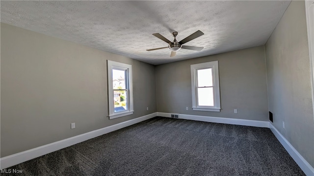 carpeted empty room with ceiling fan, a textured ceiling, and a wealth of natural light