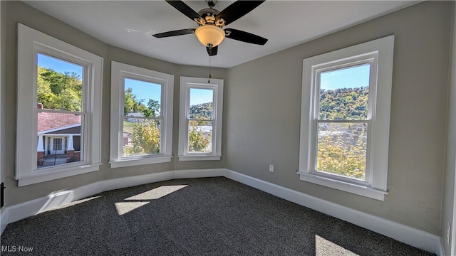 empty room with plenty of natural light, carpet, and ceiling fan