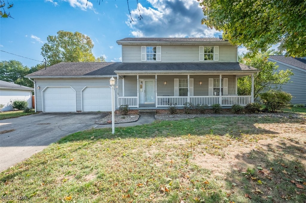 view of front of home with a garage, a porch, and a front lawn