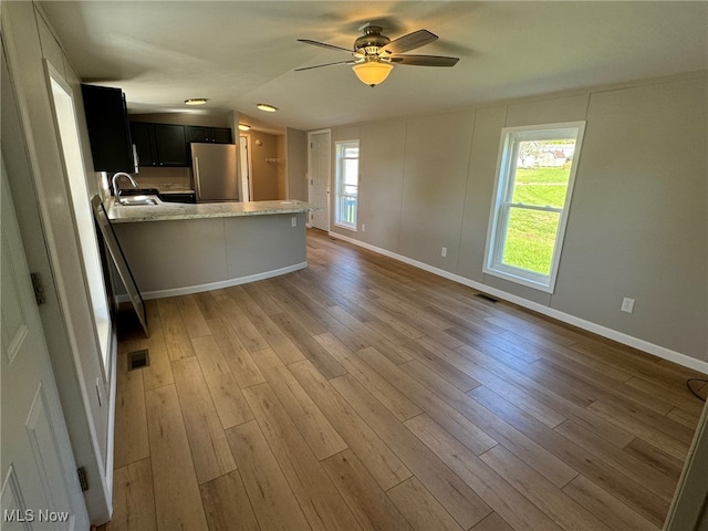 unfurnished living room featuring light hardwood / wood-style flooring, ceiling fan, and sink