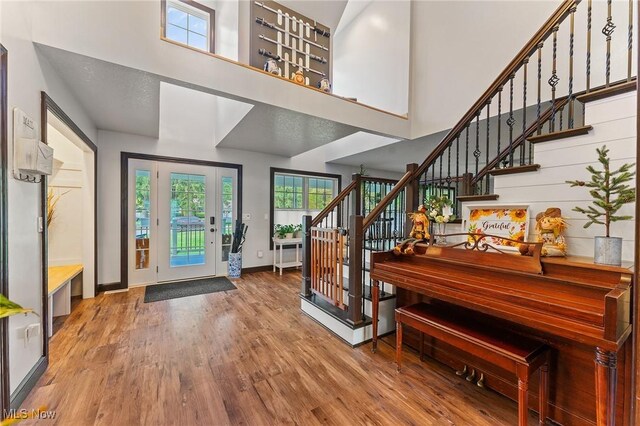 entrance foyer with wood-type flooring, a textured ceiling, and a towering ceiling