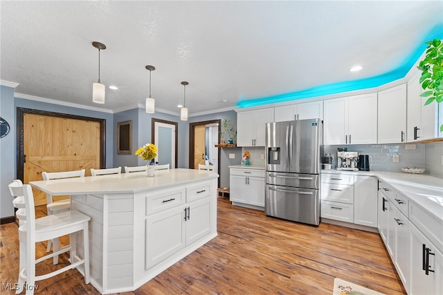 kitchen featuring pendant lighting, light hardwood / wood-style flooring, a breakfast bar, white cabinets, and stainless steel fridge with ice dispenser