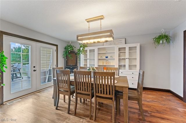 dining room featuring french doors, wood-type flooring, and a textured ceiling