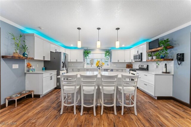 kitchen with white cabinets, decorative light fixtures, stainless steel appliances, dark hardwood / wood-style floors, and a breakfast bar area