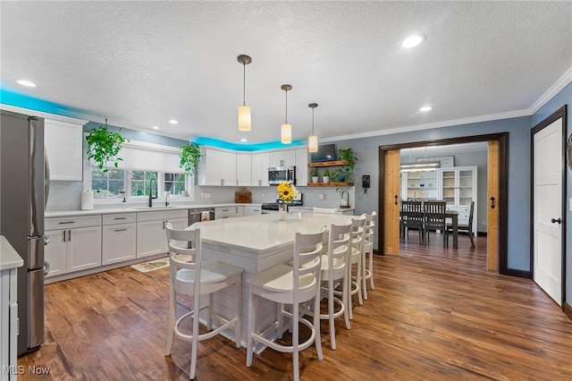 kitchen featuring pendant lighting, white cabinetry, dark hardwood / wood-style flooring, stainless steel appliances, and a textured ceiling