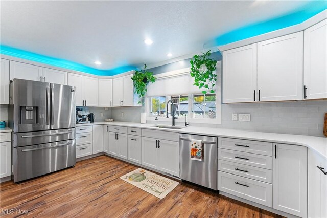 kitchen featuring appliances with stainless steel finishes, dark wood-type flooring, sink, and white cabinets