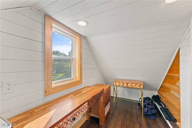 additional living space with dark wood-type flooring, wood walls, and vaulted ceiling