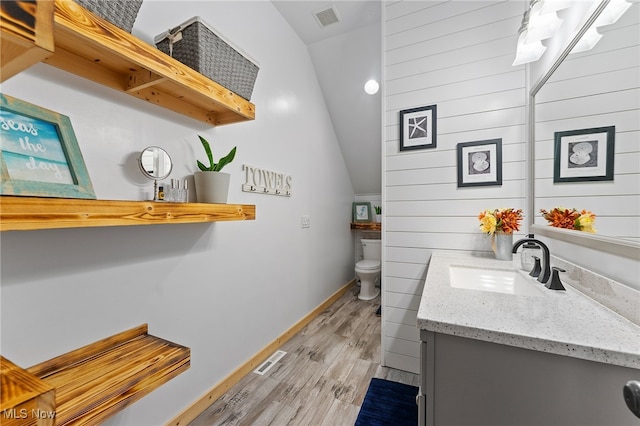 bathroom with vaulted ceiling, vanity, hardwood / wood-style floors, and toilet