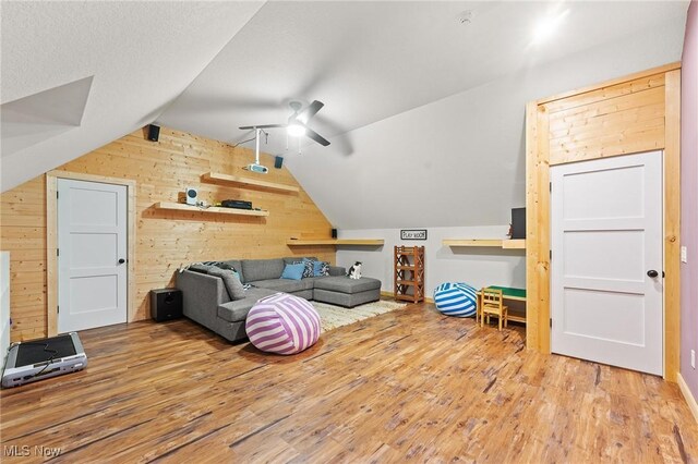 additional living space with ceiling fan, hardwood / wood-style flooring, lofted ceiling, and wood walls