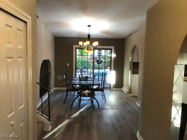 dining space with baseboard heating, dark hardwood / wood-style floors, and an inviting chandelier