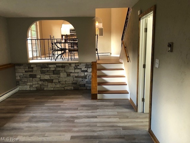 stairway featuring baseboard heating and hardwood / wood-style flooring