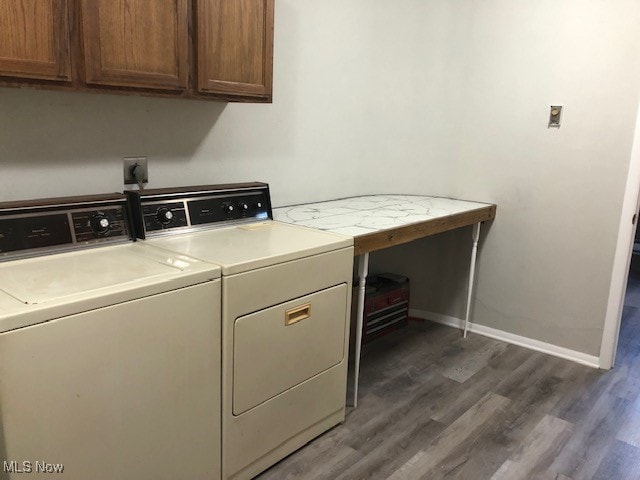 washroom featuring cabinets, washer and clothes dryer, and dark wood-type flooring