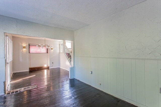 unfurnished room with hardwood / wood-style flooring and a textured ceiling