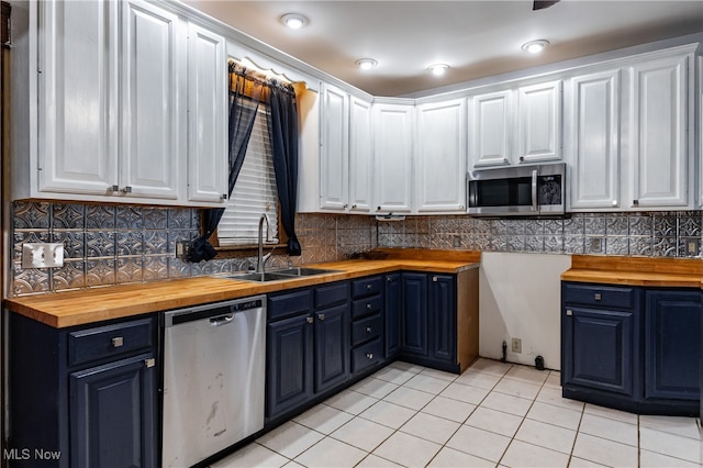 kitchen with stainless steel appliances, butcher block countertops, and white cabinetry