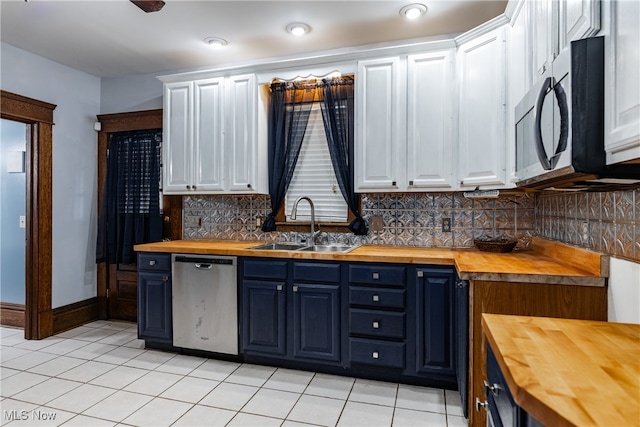 kitchen featuring blue cabinets, wood counters, stainless steel appliances, backsplash, and white cabinetry