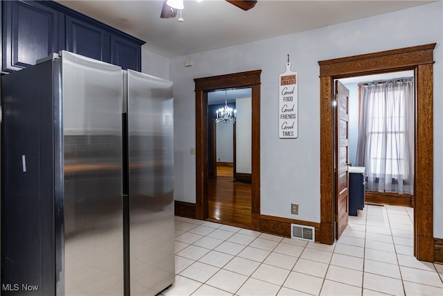 kitchen featuring ceiling fan with notable chandelier, blue cabinets, stainless steel fridge, and light tile patterned floors