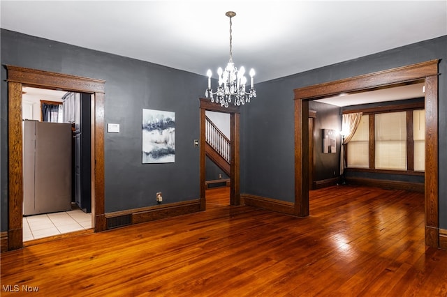 empty room with hardwood / wood-style floors and a chandelier