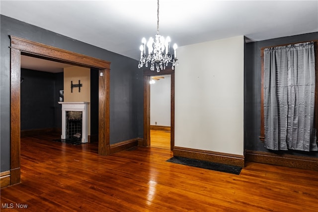 empty room featuring dark wood-type flooring and a chandelier