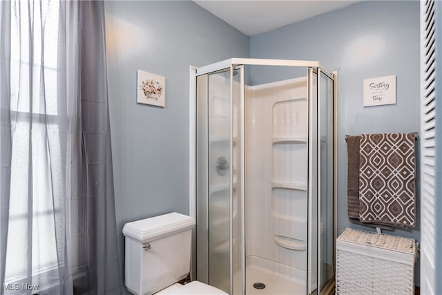 bathroom featuring a shower with shower door and toilet