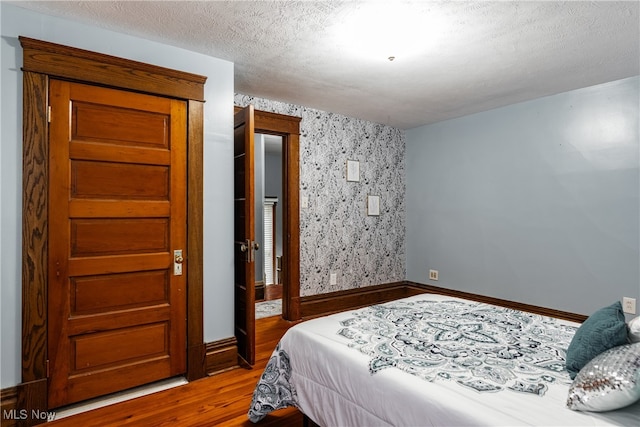 bedroom featuring hardwood / wood-style flooring and a textured ceiling