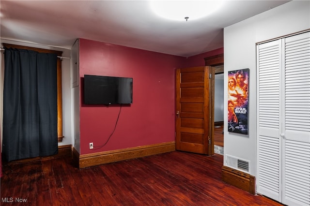 unfurnished bedroom with a closet and dark hardwood / wood-style flooring