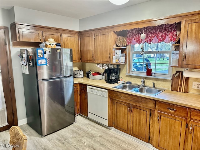 kitchen with stainless steel refrigerator, tasteful backsplash, light hardwood / wood-style flooring, sink, and dishwasher