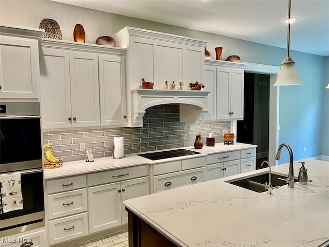 kitchen featuring white cabinets, stainless steel double oven, sink, pendant lighting, and black electric stovetop