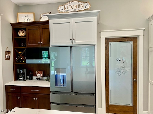 kitchen with refrigerator with ice dispenser, dark brown cabinets, and white cabinets