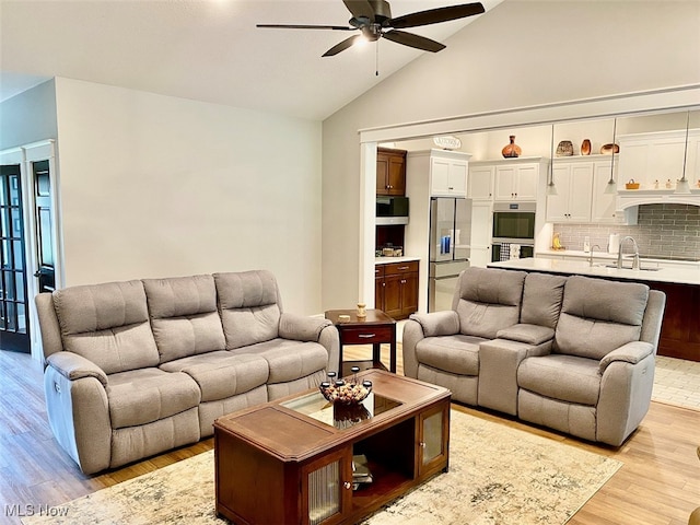 living room with ceiling fan, light wood-type flooring, and high vaulted ceiling