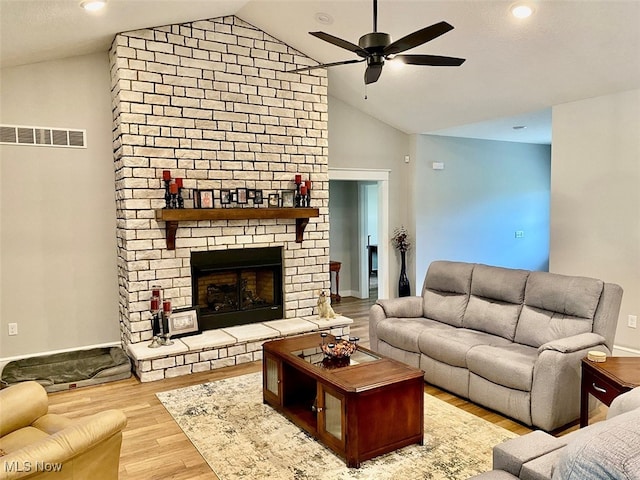 living room featuring a fireplace, vaulted ceiling, light hardwood / wood-style flooring, and ceiling fan