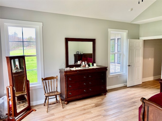 living area featuring lofted ceiling, plenty of natural light, and light hardwood / wood-style flooring