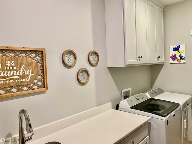 laundry area featuring washing machine and dryer, cabinets, and sink