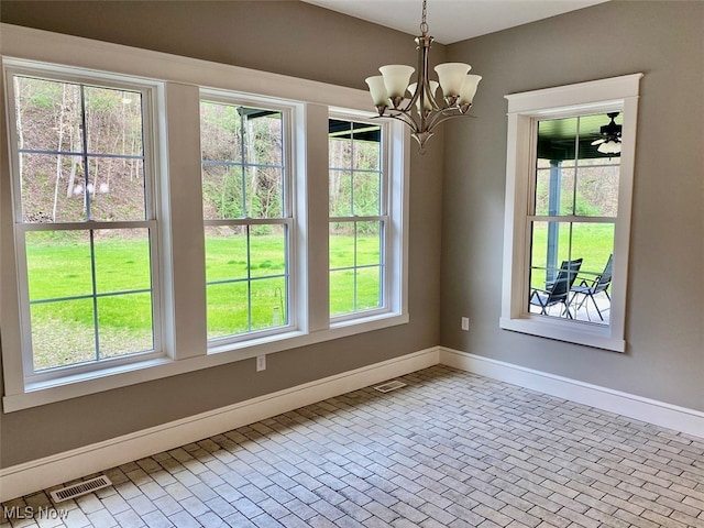 unfurnished dining area featuring ceiling fan with notable chandelier