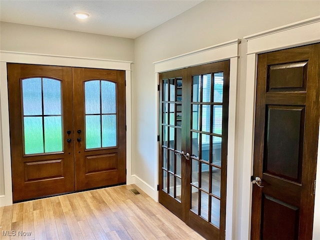 entrance foyer with a healthy amount of sunlight, french doors, and light hardwood / wood-style flooring