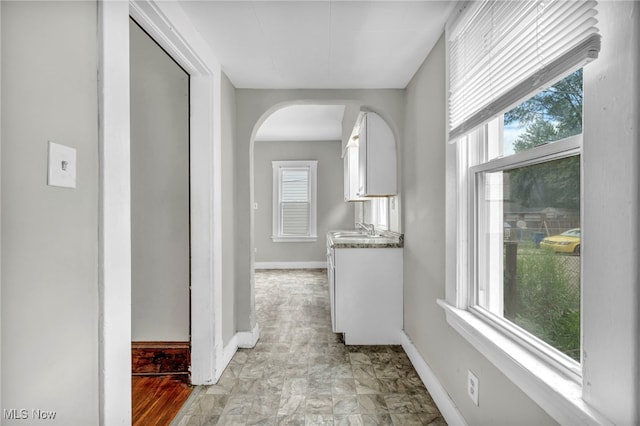 corridor featuring sink and a wealth of natural light