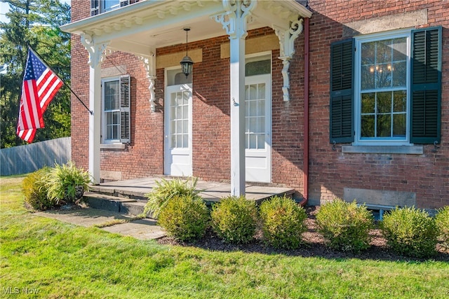 doorway to property featuring a yard and covered porch