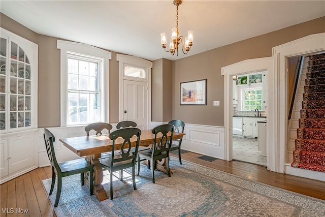 dining area with wood-type flooring, a notable chandelier, and sink